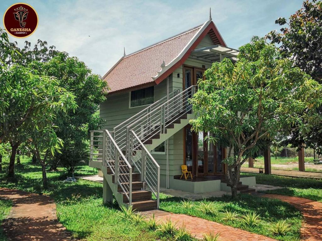 a green house with a staircase in front of it at Ganesha Kampot Resort in Kampot
