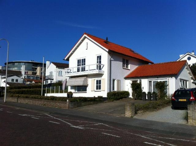 een wit huis met een oranje dak op een straat bij Studio Sunrise in Zandvoort