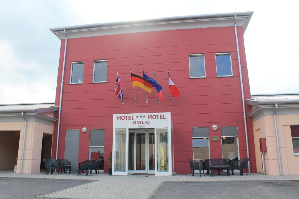 a red building with flags in front of it at Hotel Motel Giglio in Viadana