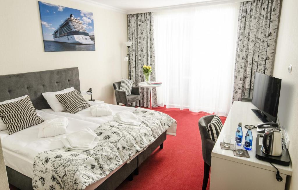 Pokój hotelowy z dużym łóżkiem i telewizorem w obiekcie Grand Kapitan Medi Spa - POKOJE OZONOWANE w mieście Ustronie Morskie