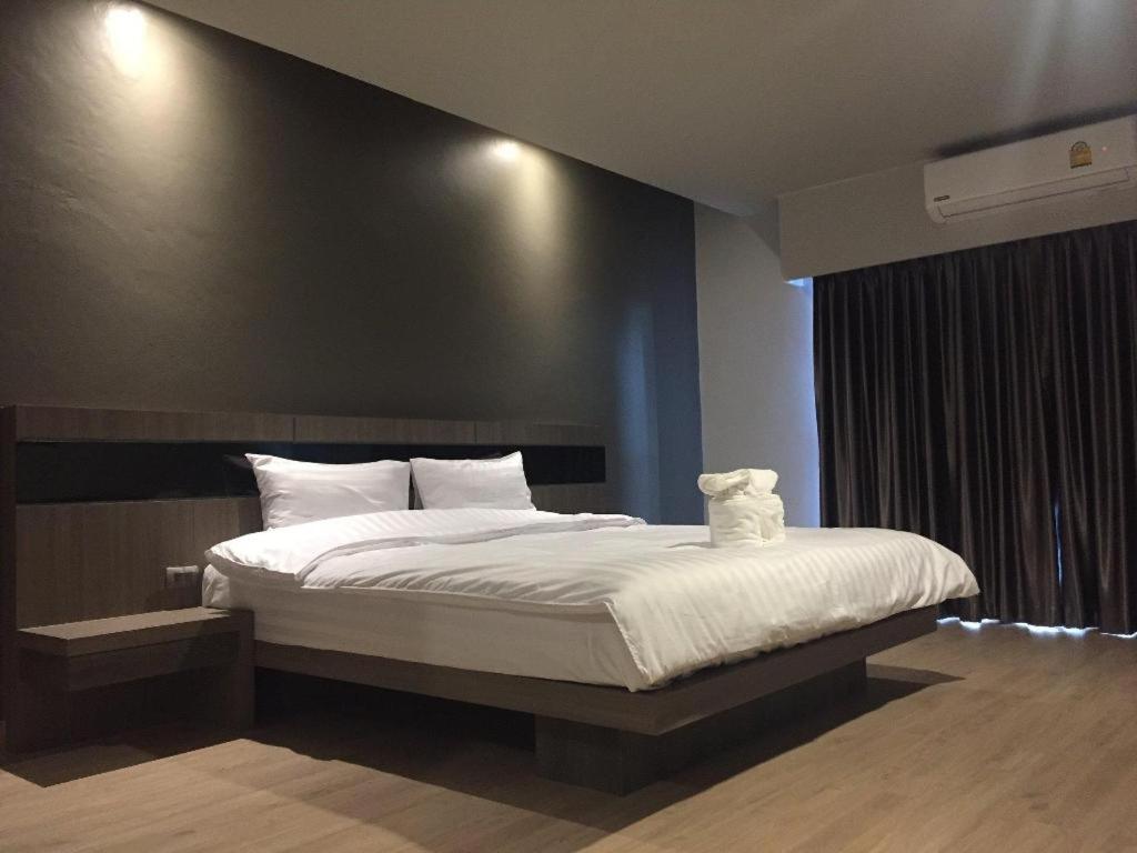 a bedroom with a large bed with a black wall at Melodi Hotel Dannok in Sadao