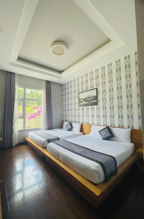 two beds sitting in a room with a window at Dalat Wind Hotel in Da Lat