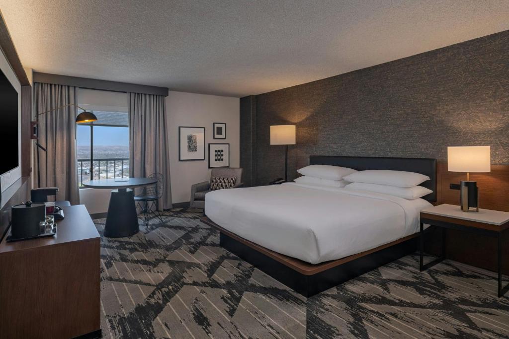 a hotel room with a large bed and a balcony at Sheraton Albuquerque Airport Hotel in Albuquerque