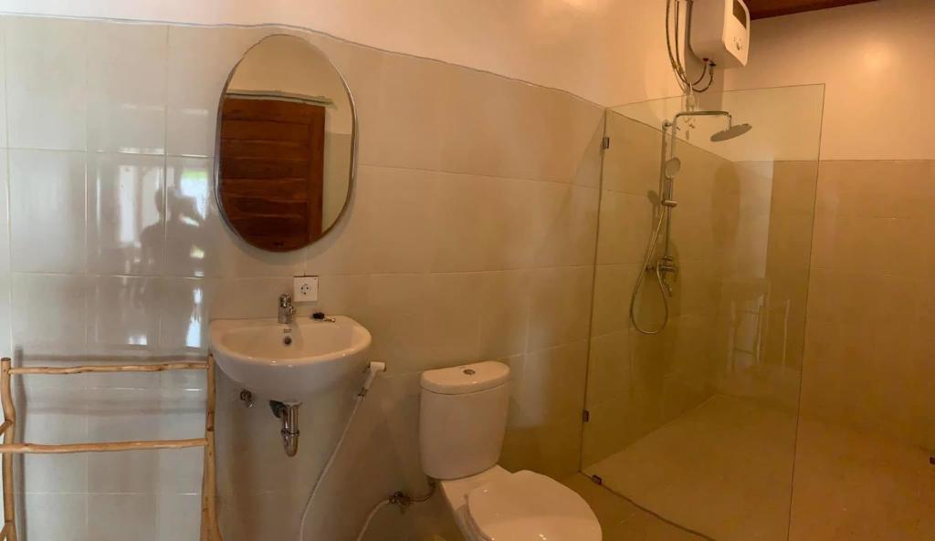 a bathroom with a toilet and a sink and a mirror at Tri Putri Villa in Badung