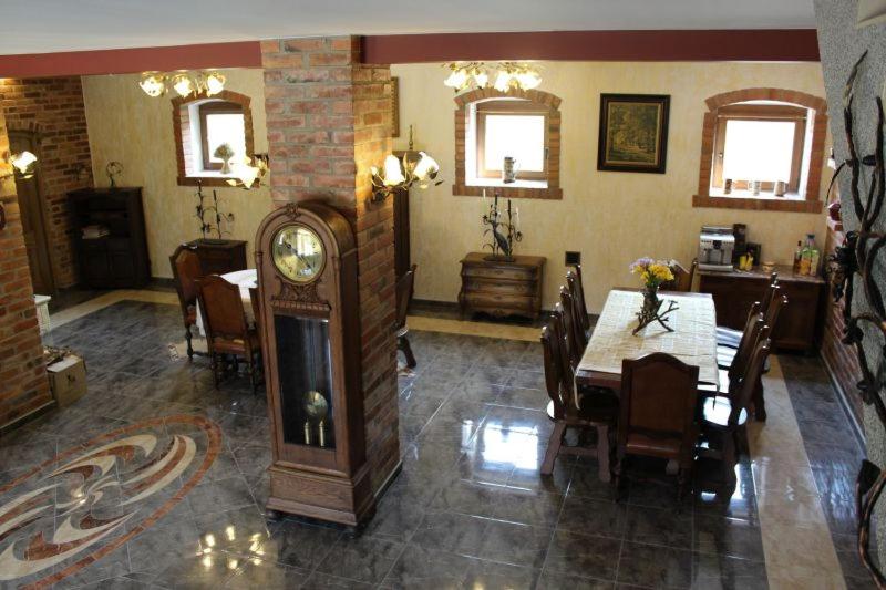 ein Esszimmer mit einem Tisch und einer Großvater-Uhr in der Unterkunft Pensjonat Florentyna in Warnice
