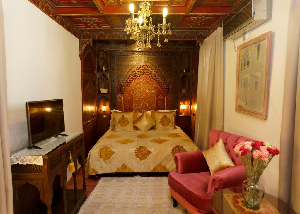 a bedroom with a bed and a couch and a television at Riad Cherifa in Chefchaouene