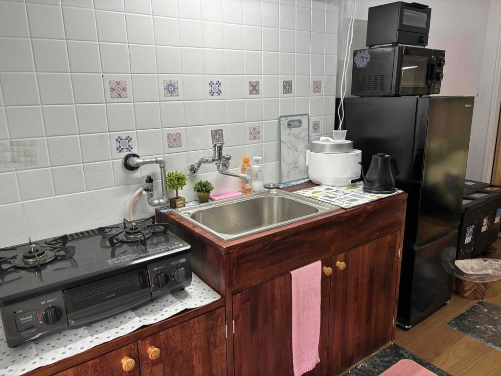 a kitchen with a sink and a stove at I Love SHIN-OSAKA in Osaka