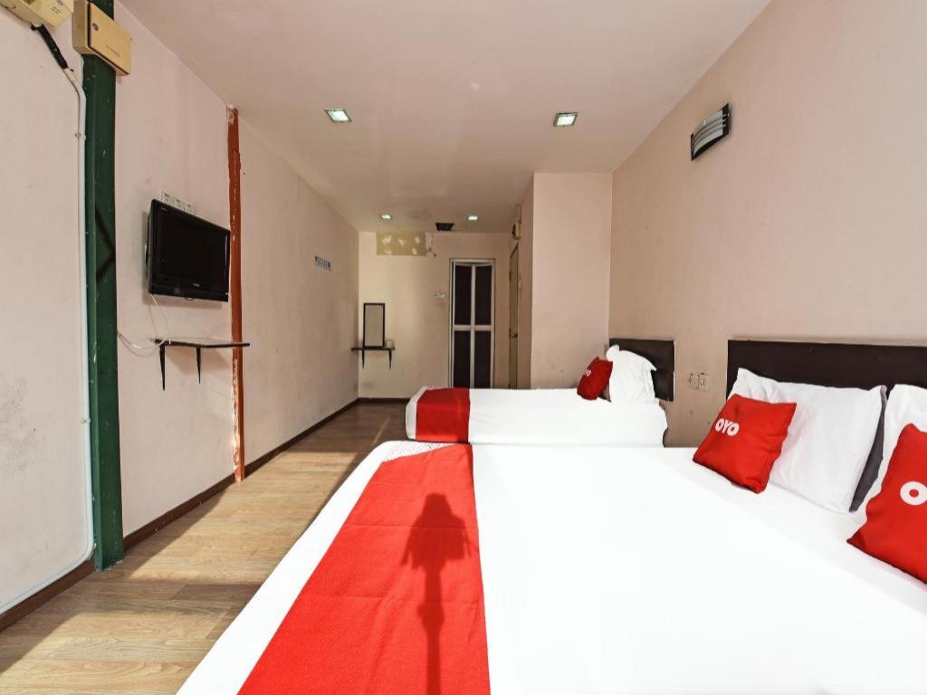 a room with two beds with red pillows and a television at OYO 90643 Gks Hotel in Seremban