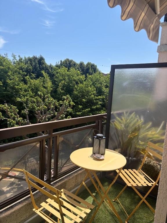 une table et des chaises sur un balcon arboré dans l'établissement Studio de vacances paisible et central, à Mandelieu-la-Napoule