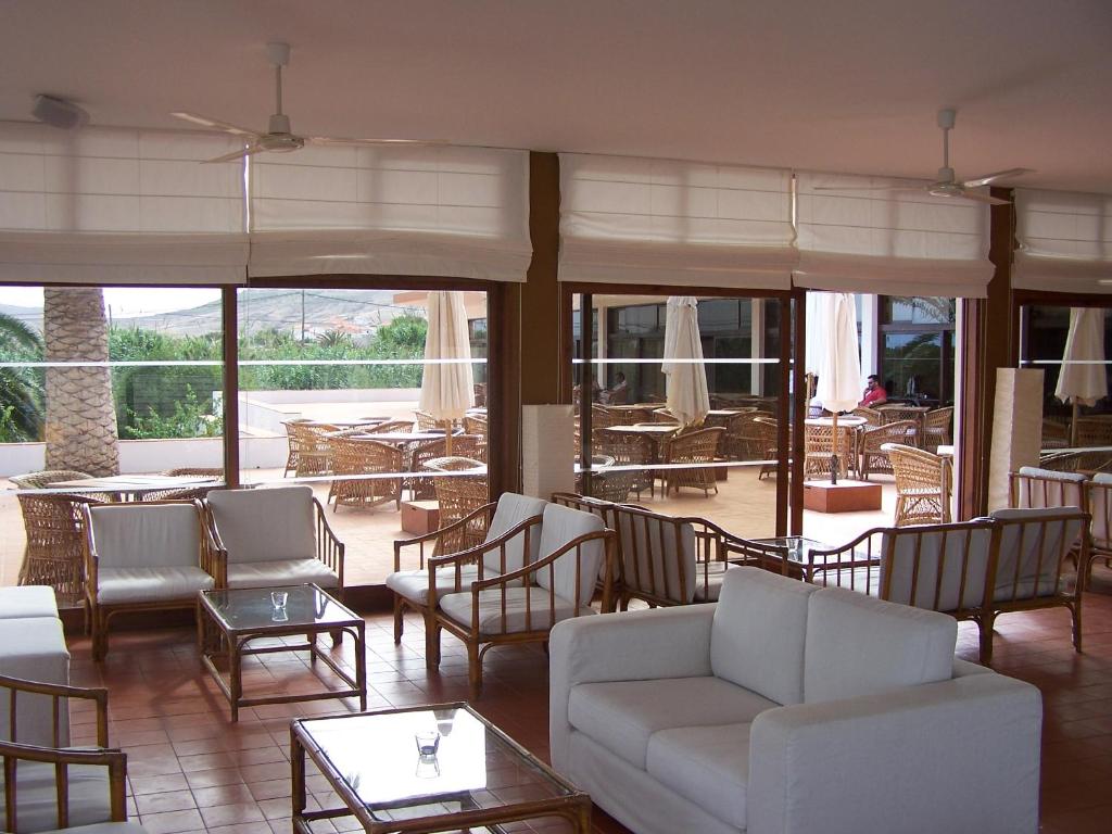 a living room with chairs and tables and windows at Hotel Porto Santo & Spa in Porto Santo