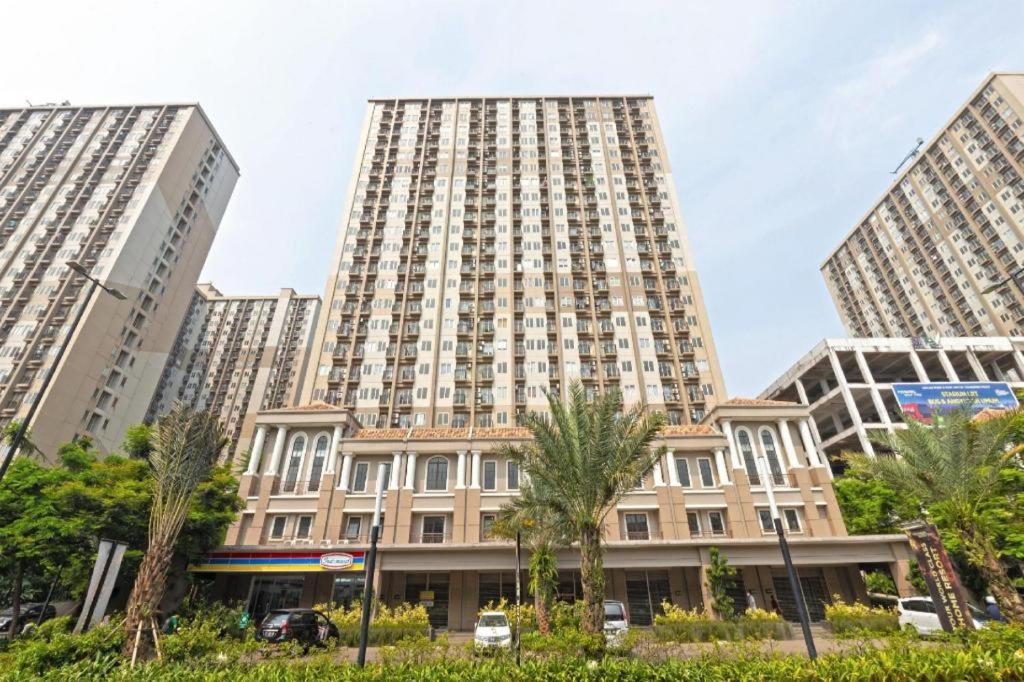 a tall building with palm trees in front of it at OYO 94080 Apartemen Podomoro Golf View Palito in Tjikuda Tiga