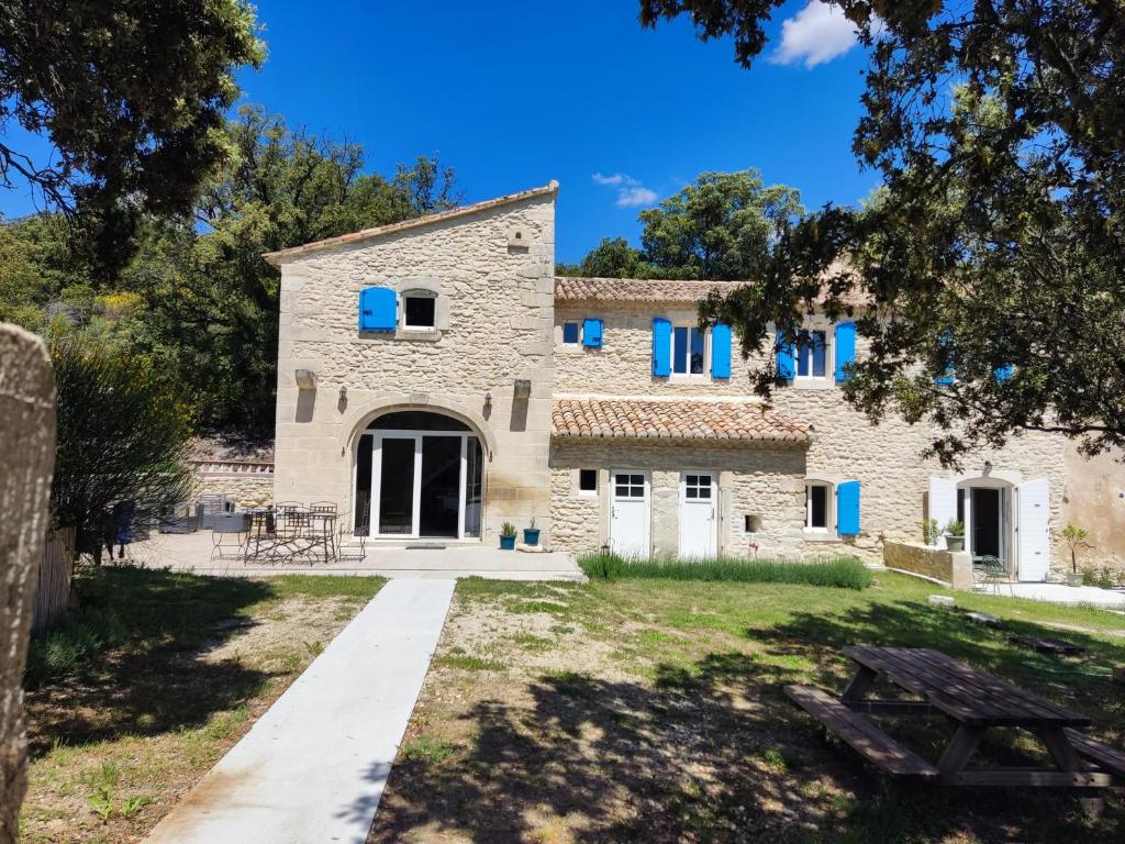 une vieille maison en pierre avec des fenêtres bleues et une table de pique-nique dans l'établissement Beaux Yeux, à Montségur-sur-Lauzon
