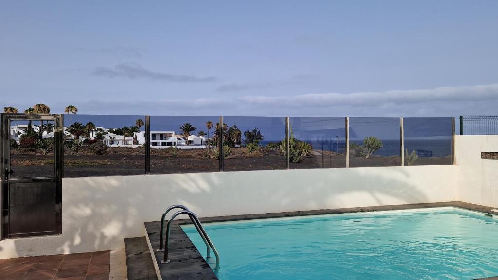 a swimming pool with a view of the ocean at Bungalow El Mar in Teguise