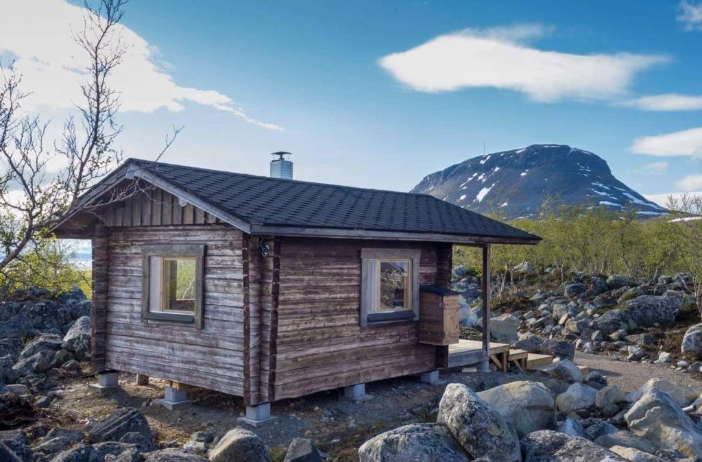 een kleine hut met een berg op de achtergrond bij Wilderness Hut Lake Tsahkal in Kilpisjärvi