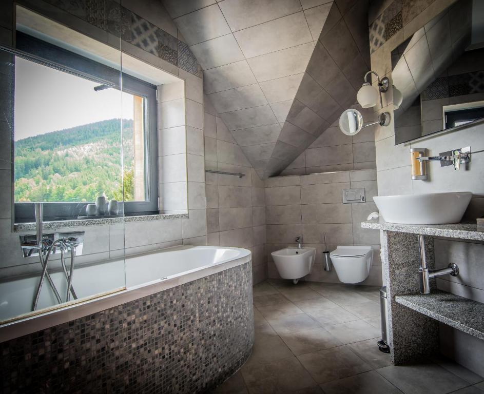 łazienka z wanną, 2 toaletami i oknem w obiekcie Hotel Friuli w mieście Harrachov