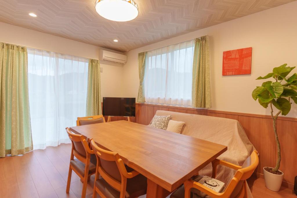 ein Esszimmer mit einem Holztisch und Stühlen in der Unterkunft K Cottage in Fujikawaguchiko