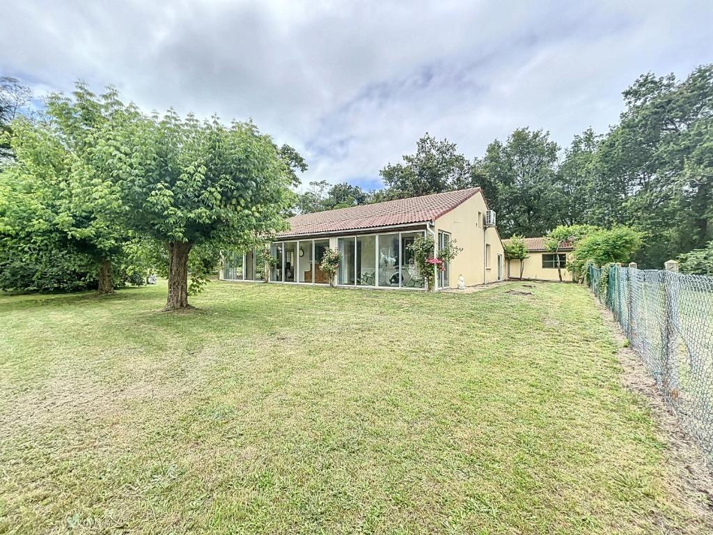 une maison avec un arbre et une clôture dans l'établissement Charmante maison avec jardin, à Bussac-Forêt