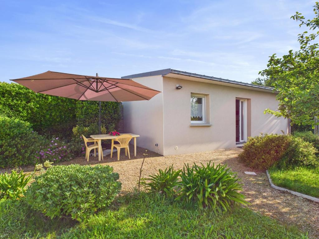 un patio avec une table et un parasol dans l'établissement Maisonnette 4 personnes - 300m de la plage, à Penvénan