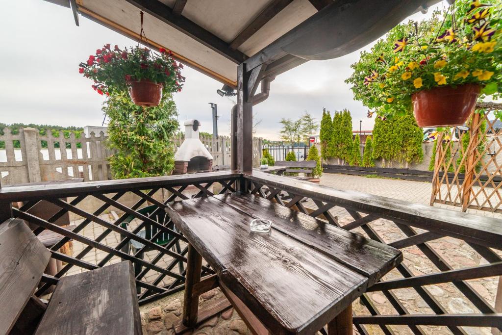 a wooden bench on a balcony with potted plants at Domek nad jeziorem, Mikołajki in Mikołajki