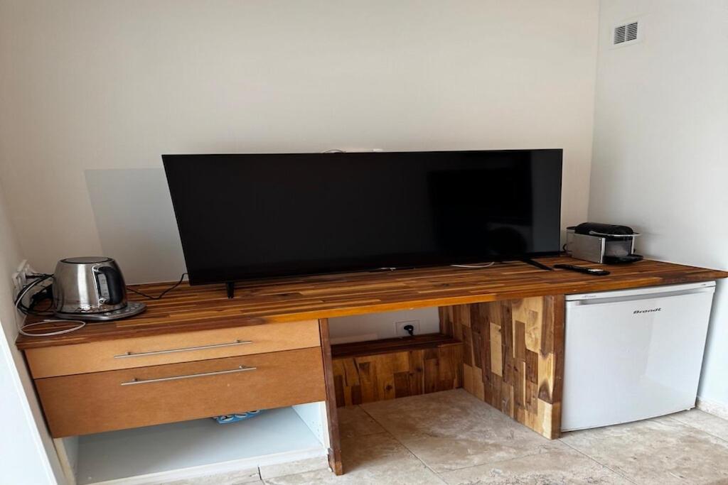Elle comprend un bureau en bois et une télévision à écran plat. dans l'établissement Furnished 2-room apartment with terrace, au Cap d'Agde