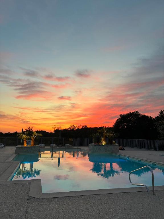 une piscine avec un coucher de soleil en arrière-plan dans l'établissement Domaine de la Faurie, à Séniergues