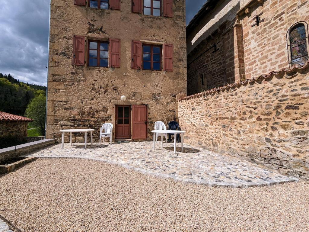 two tables and chairs in front of a building at Gîte de charme 10 pers. à Saint-Vert - Nature préservée, 4 chambres, jardin clos - FR-1-582-307 in Saint-Vert