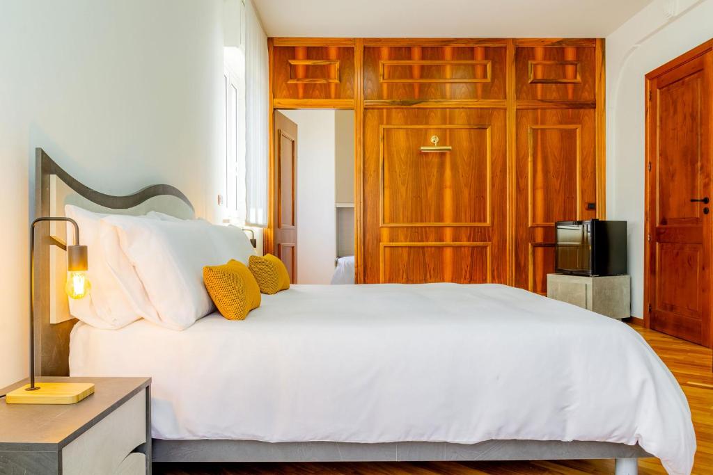 Un dormitorio con una cama blanca y un televisor. en I Barcaioli, en Giardini Naxos