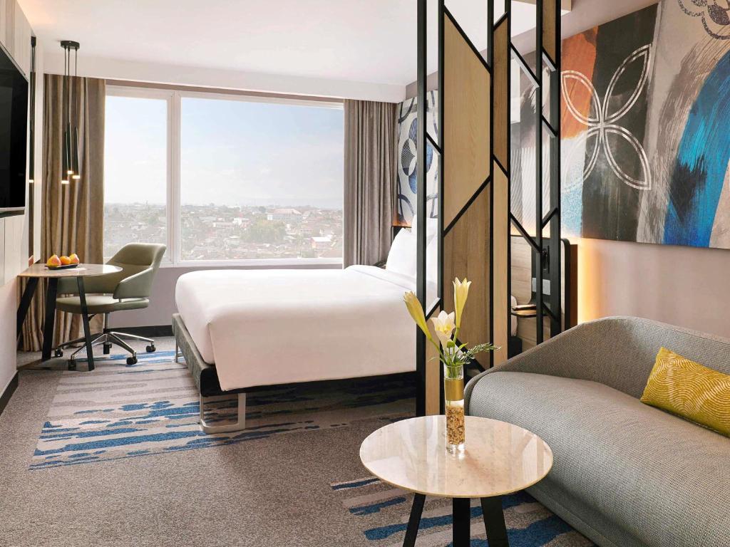 a hotel room with a bed and a couch at Novotel Suites Yogyakarta Malioboro in Yogyakarta