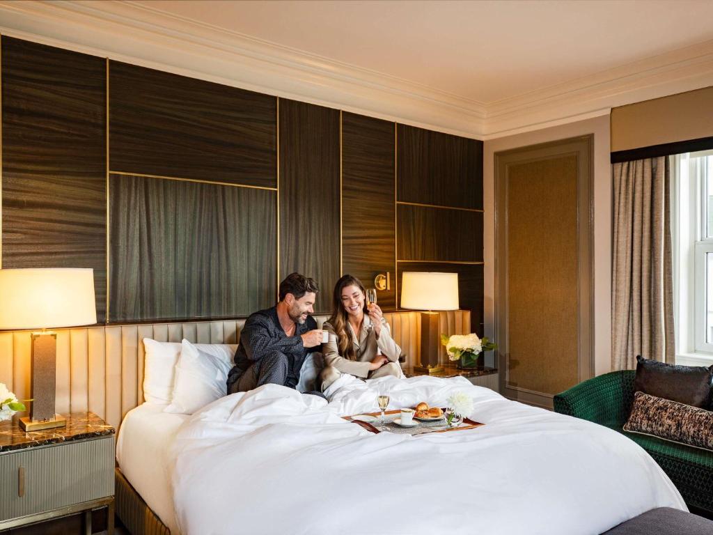 a man and woman sitting on a bed at Fairmont Chateau Laurier in Ottawa