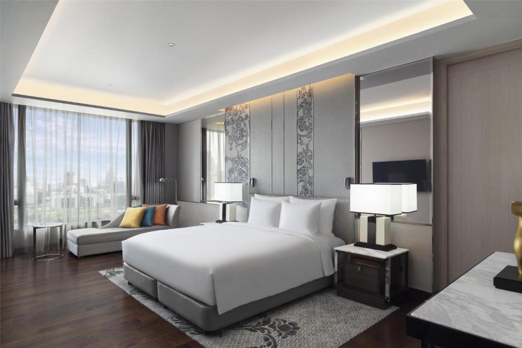 a bedroom with a large white bed and a couch at Sindhorn Kempinski Hotel Bangkok in Bangkok