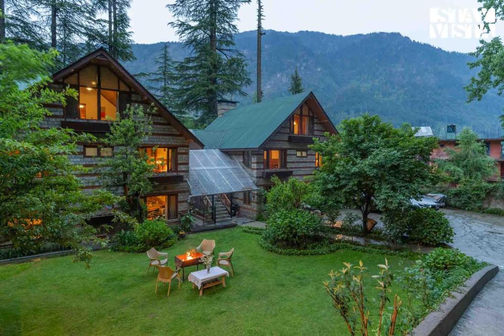 ein Blockhaus mit einem Tisch und Stühlen im Hof in der Unterkunft StayVista at Retreat Cottages with Lawn, Bonfire in Manali
