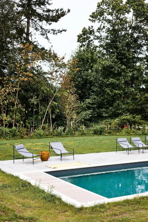 une piscine avec quatre chaises à côté d'un champ dans l'établissement Country House With Pool Near Rambouillet, 40 Min From Paris, à Gambais