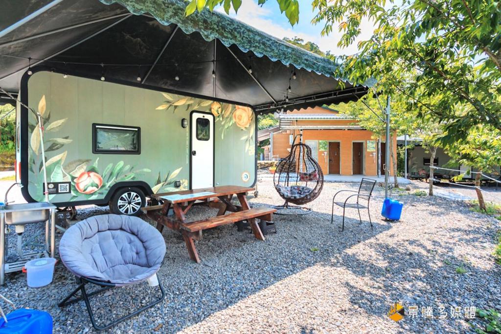 a green trailer parked under a tent with a chair at 太平山旅居 in Datong