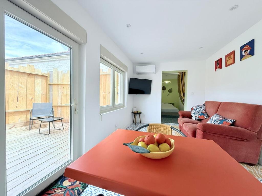 un salon avec un bol de fruits sur une table rouge dans l'établissement L'Entre-Rives, à Rochefort