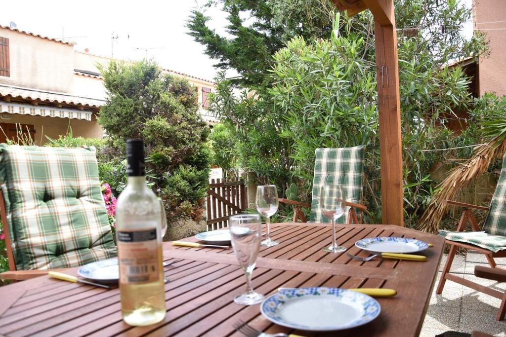 - une table en bois avec une bouteille de vin et des verres dans l'établissement Maison 3 pièces - Gruissan Ayguades AY060-075, à Vires