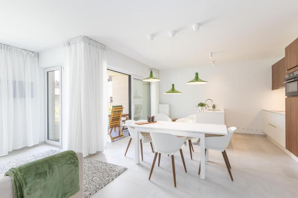 a kitchen and dining room with a white table and chairs at LECOMTE - The Shoreline Green 153 in Ostend