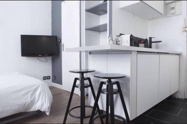- une chambre avec deux tabourets de bar et un lit dans l'établissement Studio hyper centre historique Quai bourgeois, à Bordeaux
