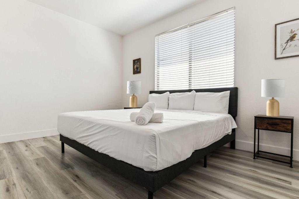 ein weißes Schlafzimmer mit einem großen Bett mit weißer Bettwäsche in der Unterkunft Glendale CozySuites - Westgate with pool 10 in Glendale
