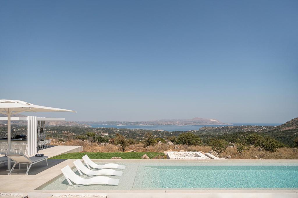 a villa with a swimming pool with chairs and an umbrella at Nature & Beauty Villa in Xirostérnion