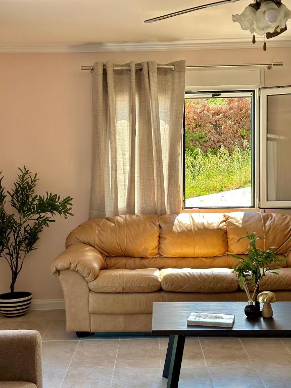 a brown leather couch in a living room with a window at Perl's Apartment in Póndi