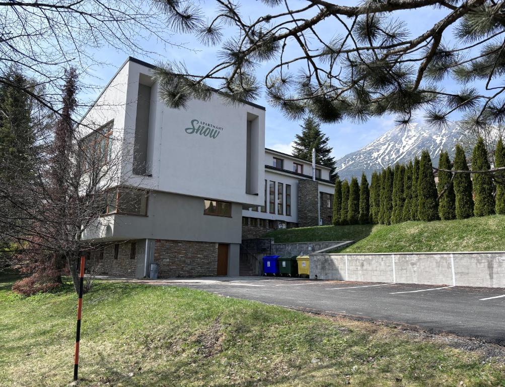 a building with a sign on the side of a road at Apartmány Snow v centre Starého Smokovca in Smokovce