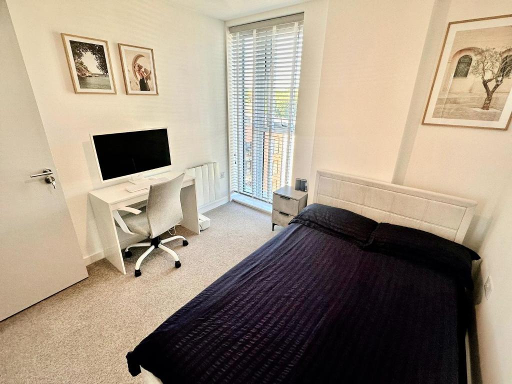 a bedroom with a bed and a desk and a television at City Centre Penthouse Bedroom in Birmingham