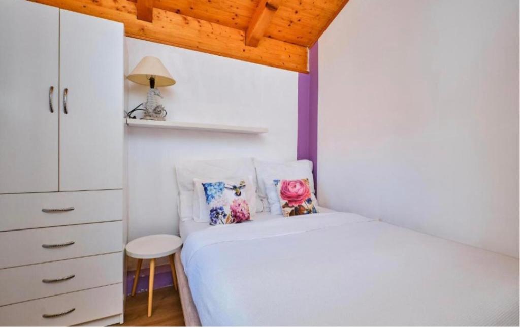 a bedroom with a white bed and a white cabinet at ILOVIK FLOWER in Ilovik