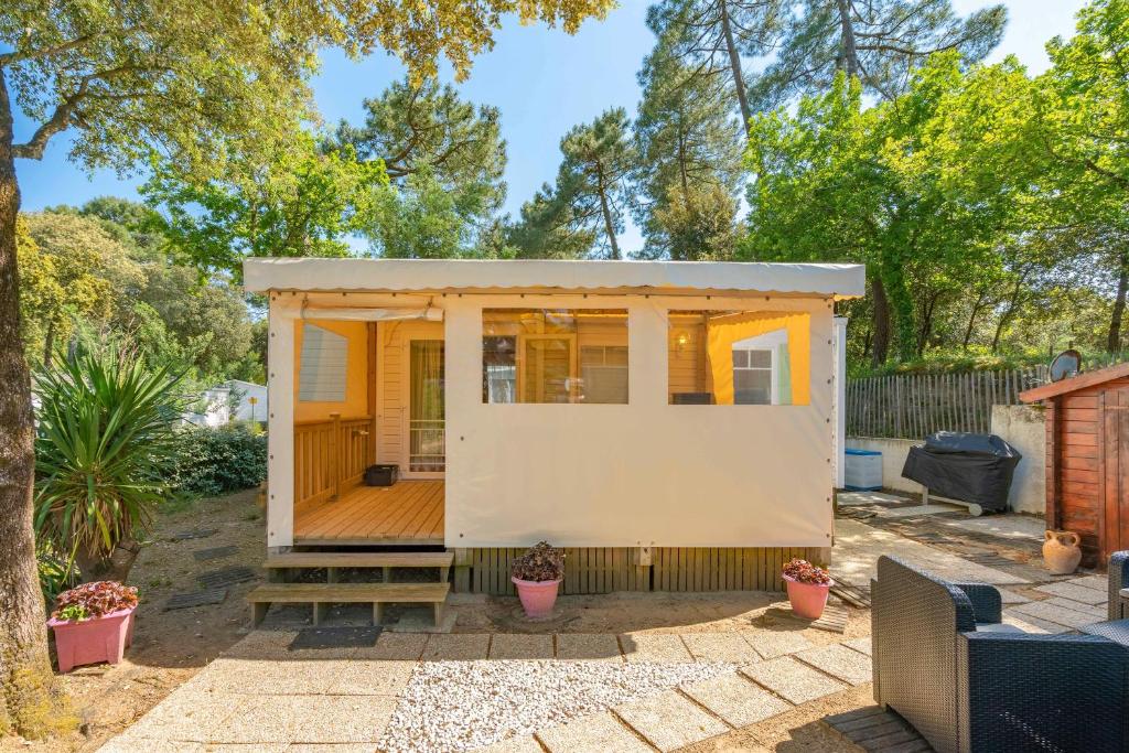 une petite maison avec une terrasse dans une cour dans l'établissement Mh 25 Les Genêts Ronce les bains, à La Tremblade