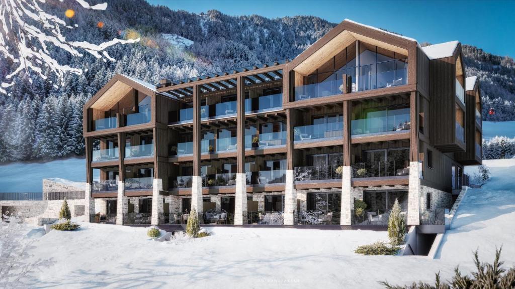 a building in the snow with mountains in the background at Luxury B&B August in Ortisei