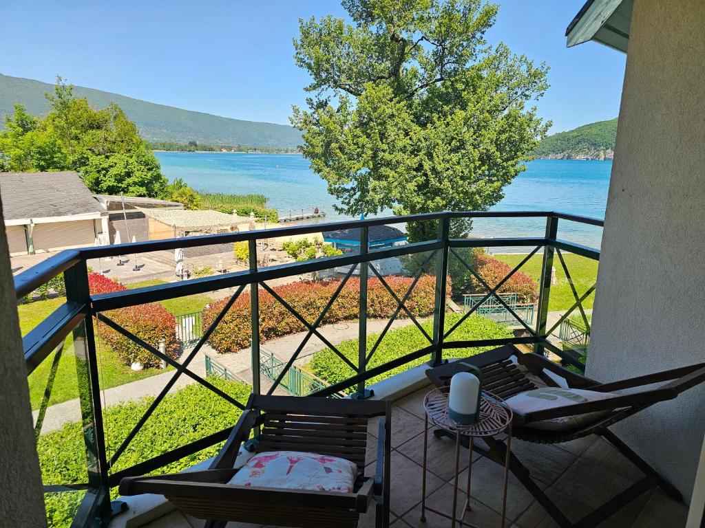 een balkon met 2 stoelen en uitzicht op het water bij Superbe Duplex Vue Lac et Château avec Plage et parking Privés in Duingt