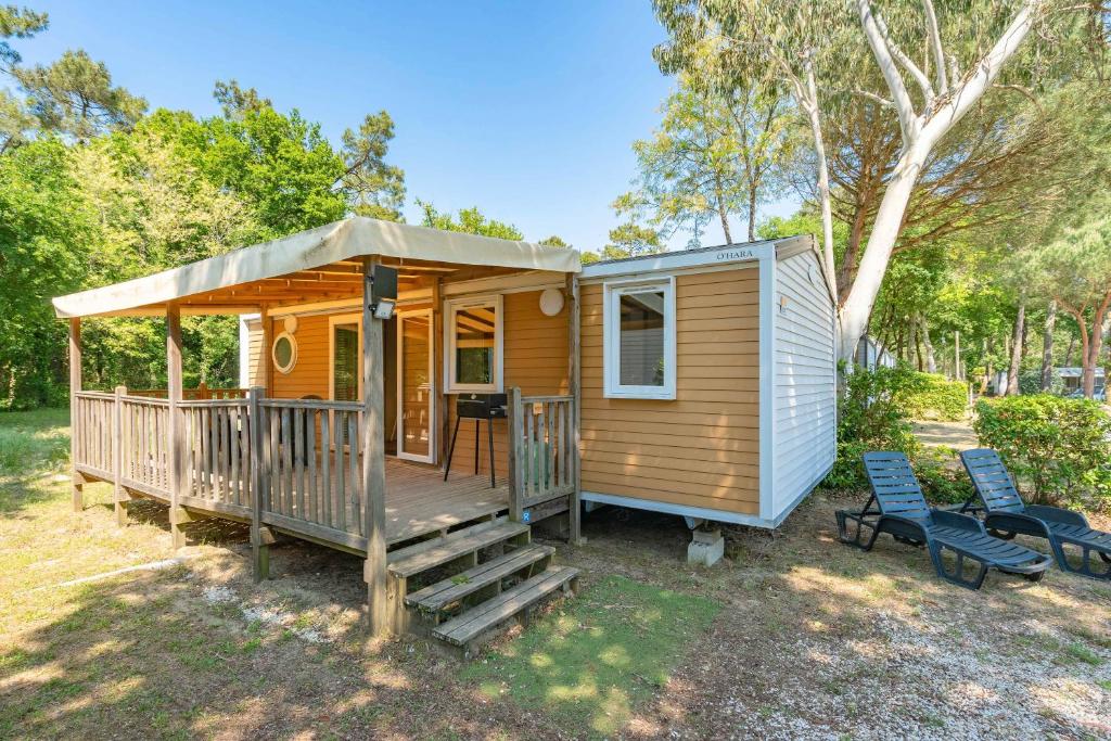 une petite maison avec une terrasse couverte et 2 chaises dans l'établissement Mh E37 La Pinède aux Mathes, aux Mathes