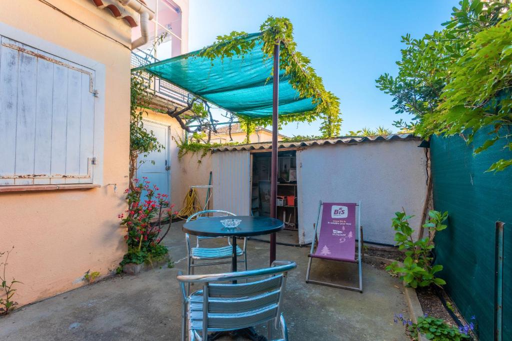 een patio met een tafel en stoelen en een blauwe baldakijn bij Chez Lina in Le Lavandou