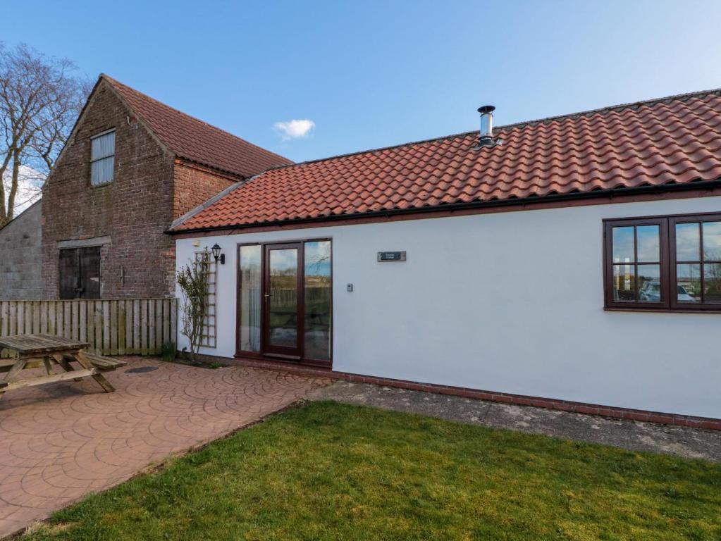 a white house with a bench and a table at Partridge Cottage in Filey