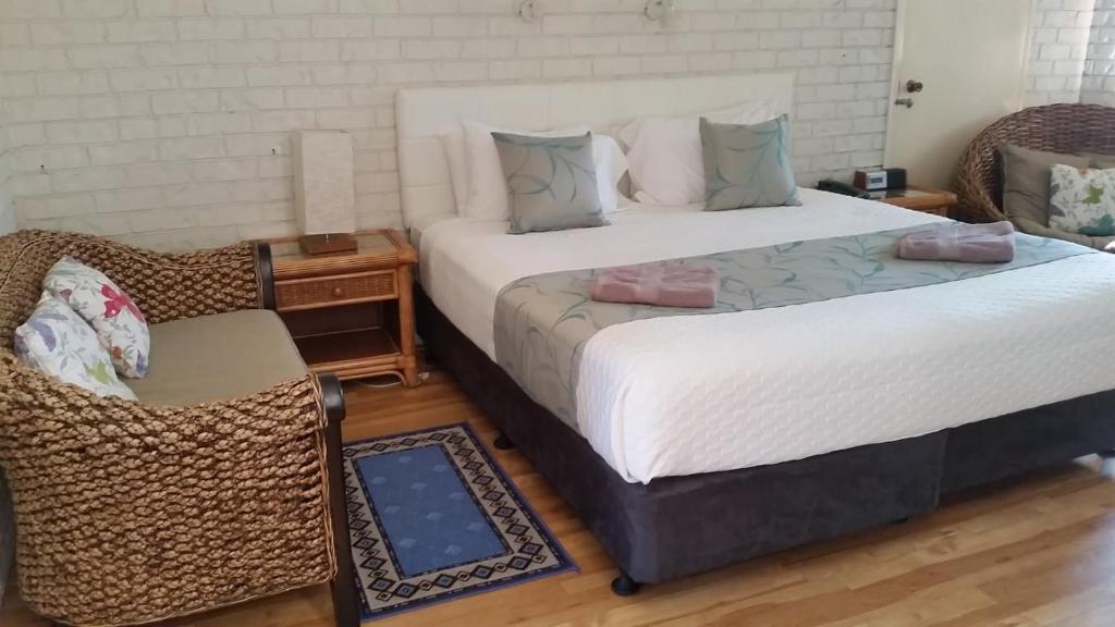 two beds in a room with a chair and a table at Holland Park Motel in Brisbane